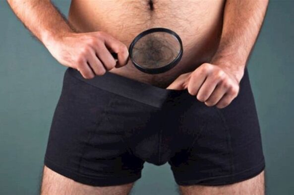 A man with a magnifying glass examines his penis and wants to make it thicker